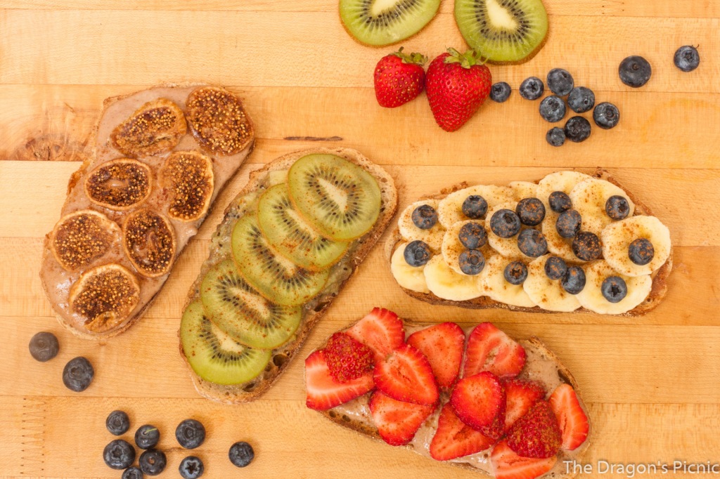 board with toasts with different toppings - dried figs, kiwi, banana and blueberry, strawberry