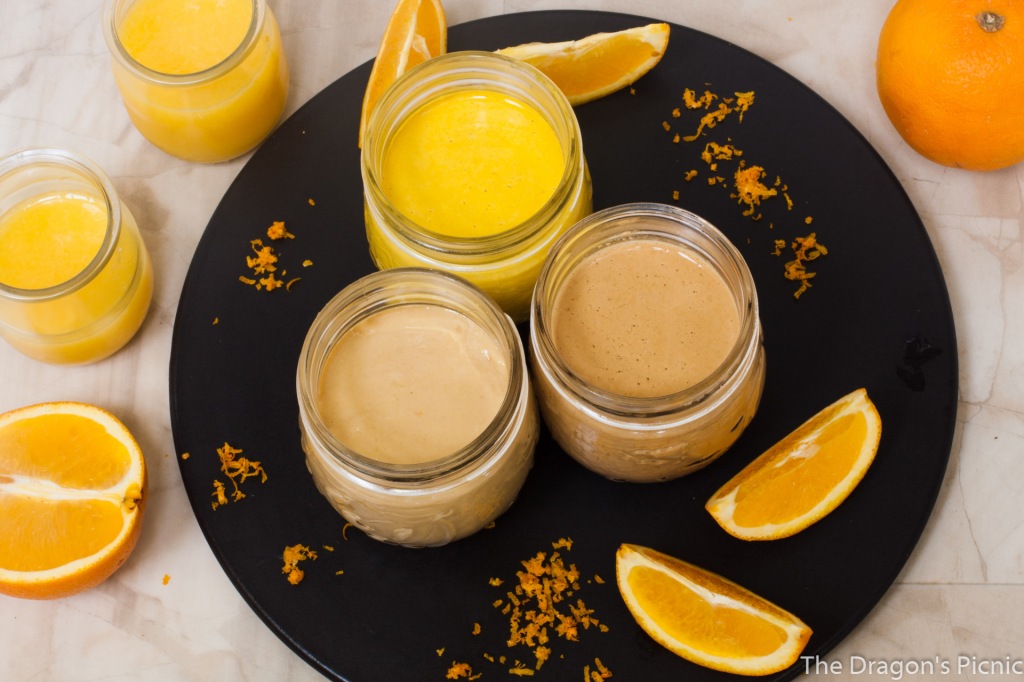 arial view of 3 jars of orange tahini based sauces with orange segments and bottles of orange juice 